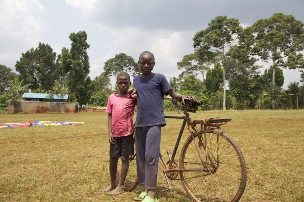 Two Children Standing Beside a Big Black Cycle