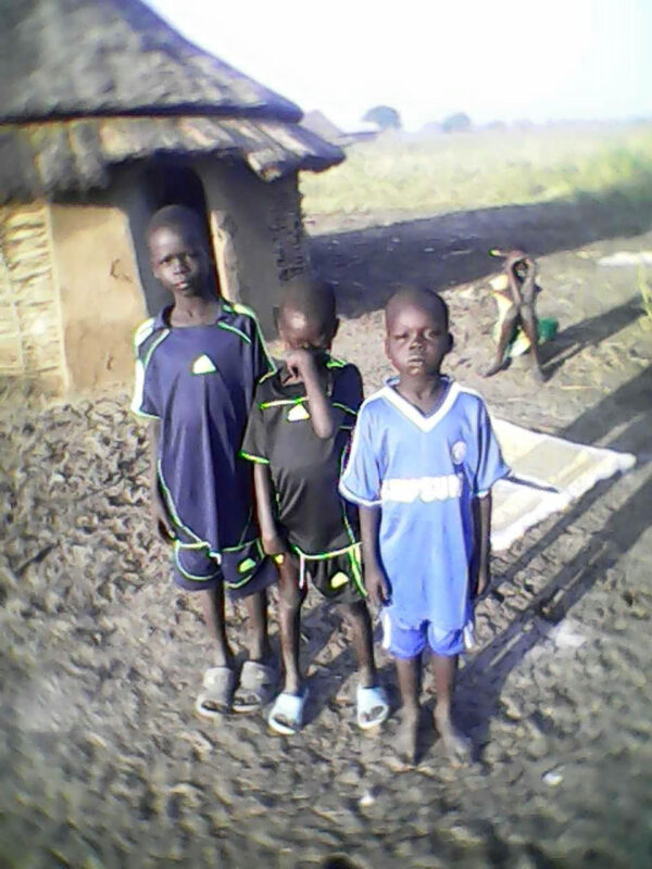 Three Children Standing Beside Each Other Outside a House